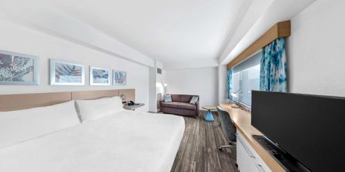 a hotel room with a bed and a flat screen tv at Hilton Garden Inn Ithaca in Ithaca