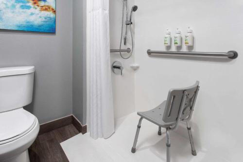 a bathroom with a toilet and a chair in it at La Quinta Inn by Wyndham Wausau in Wausau