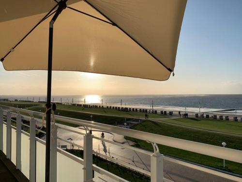 a view of the beach from a balcony with an umbrella at Haus Nordseelick Herbrechter in Norderney