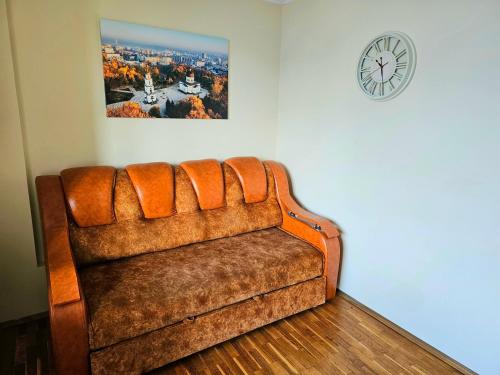 a brown couch in a room with a clock on the wall at Nice apartment on street Alexandru cel bun 108 in Chişinău