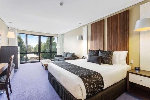 um quarto de hotel com uma cama grande e uma sala de estar em Quality Hotel Taylors Lakes em Taylors Lakes