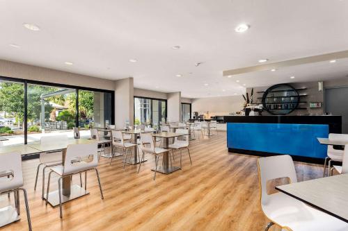a restaurant with tables and chairs and windows at Quality Hotel Taylors Lakes in Taylors Lakes