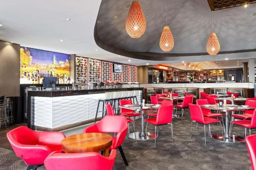a restaurant with red chairs and a bar at Quality Hotel Taylors Lakes in Taylors Lakes