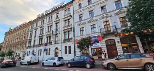 a large white building with cars parked in front of it at Pawia Apartments Centrum in Krakow