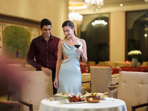 a man and a woman standing next to a table with a glass of wine at Taj Krishna in Hyderabad