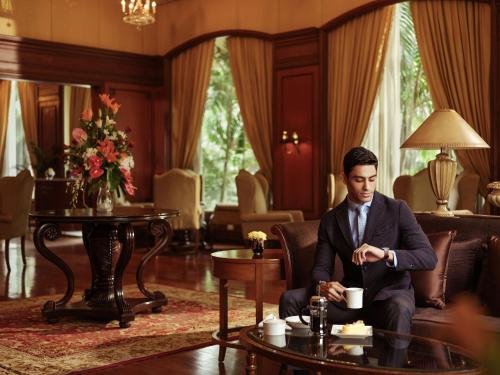 a man in a suit sitting on a couch in a living room at Taj Krishna in Hyderabad