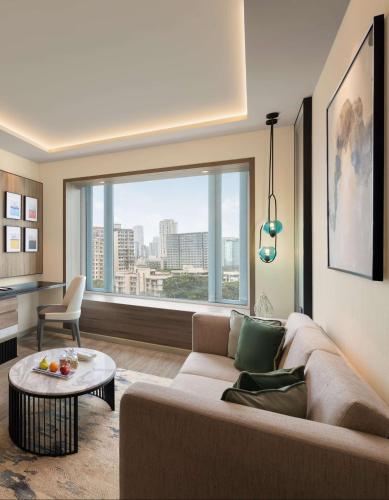 a living room with a couch and a large window at Radisson Mumbai Goregaon in Mumbai