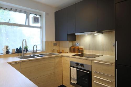 a kitchen with wooden cabinets and a sink and a window at Modern Apartment on London's Southbank in London