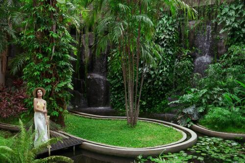 a woman standing in a garden with a waterfall at Taj Krishna in Hyderabad