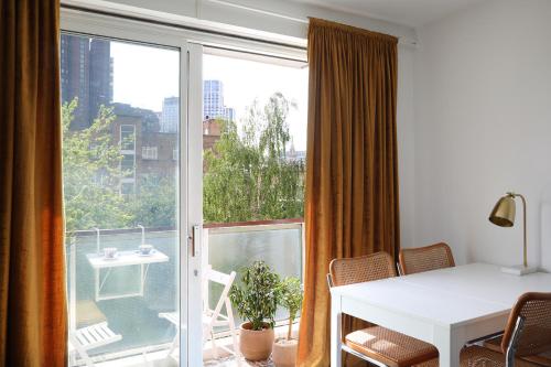 Habitación con balcón con mesa y ventana. en Modern Apartment on London's Southbank en Londres