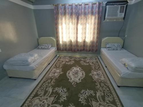 2 camas en una habitación con alfombra y ventana en Atiaf Jabal Shams house, en Misfāh