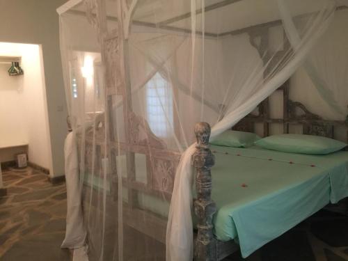 1 dormitorio con 1 cama con dosel en COTTAGE BEACHSIDE, en Malindi