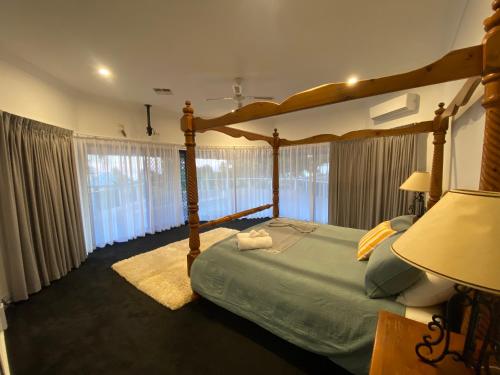 a bedroom with a canopy bed and a large window at Doyles on the Bay in Kingscote