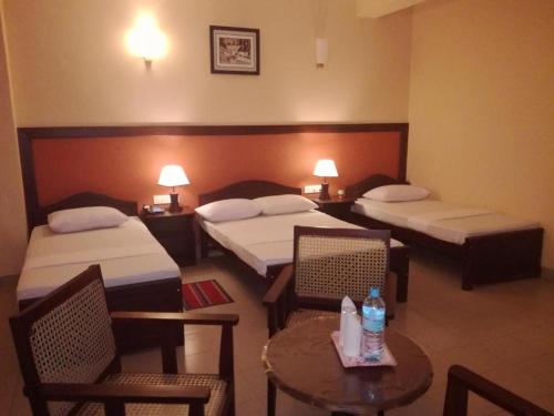 a hotel room with two beds and a table and chairs at Victory Inn Monaragala in Monaragala