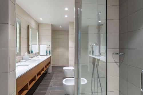 a bathroom with two sinks and a toilet and a shower at Hilton Garden Inn Tbilisi Chavchavadze in Tbilisi City
