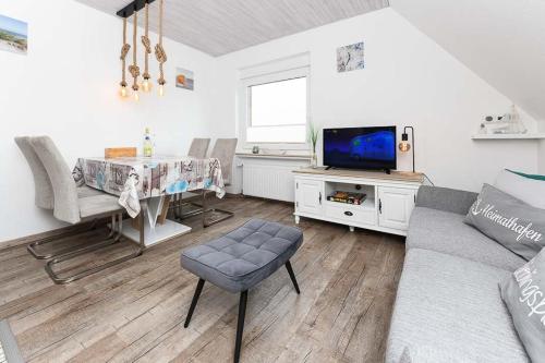 ein Wohnzimmer mit einem Sofa, einem Tisch und einem TV in der Unterkunft Ferienwohnungen Haus Boje in Neuharlingersiel