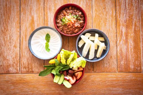a table with three bowls of food and a plate of cheese at Liwa Hotel in Mezairaa