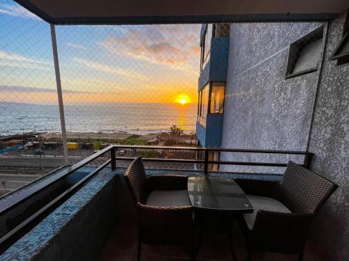 stół i krzesła na balkonie z widokiem na ocean w obiekcie Departamento Los Delfines w mieście Iquique