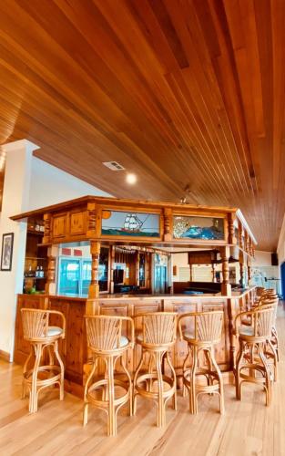 a bar with wooden chairs and a wooden ceiling at Doyles on the Bay in Kingscote