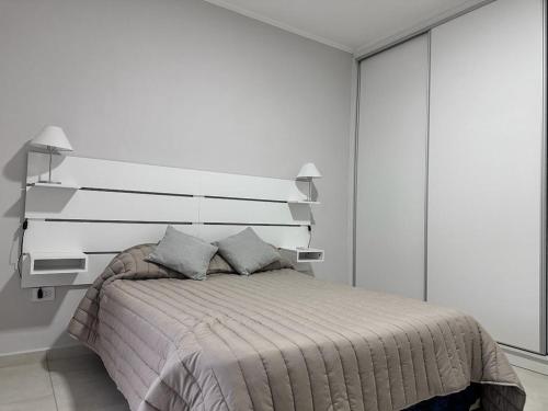 a white bedroom with a bed with a white headboard at Riffel 3 in Libertador San Martín
