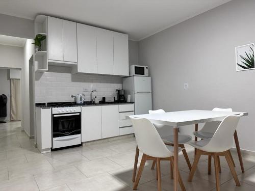 cocina con armarios blancos, mesa y sillas en Riffel 3 en Aldea Camarero