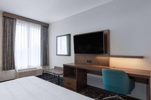 a hotel room with a bed and a desk with a television at La Quinta Inn & Suites by Wyndham Centralia in Centralia