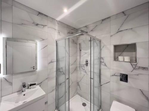 La salle de bains blanche est pourvue d'une douche et d'un lavabo. dans l'établissement Stylish Windsor Getaway w/ Balcony - Free Parking, à Windsor