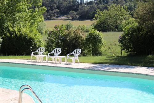 três cadeiras brancas sentadas ao lado de uma piscina em Lou Penequet a charming Mas in Provence with shared pool countryside em Flayosc