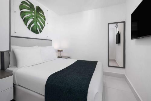 GRAN HOTEL EUROPA TRADEMARK COLLECTION by WYNDHAM في سانتو دومينغو: غرفة نوم بيضاء مع سرير أبيض ومرآة