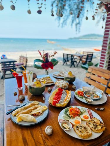 einen Tisch mit Teller mit Speisen am Strand in der Unterkunft Full Moon Bungalow Resort Koh Chang Ranong in Koh Chang Ranong