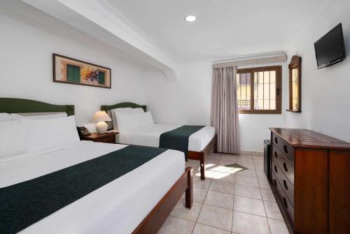 a hotel room with two beds and a television at Gran Hotel Europa Santo Domingo Trademark Collection by Wyndham in Santo Domingo