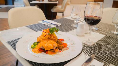 a plate of food on a table with a glass of wine at Hilton Garden Inn Panama City Downtown, Panama in Panama City