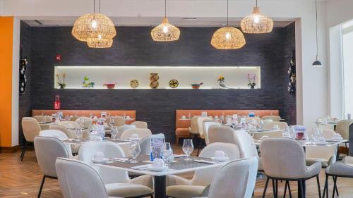 une salle à manger avec des tables blanches, des chaises et des lumières dans l'établissement Hilton Garden Inn Panama City Downtown, Panama, à Panama City