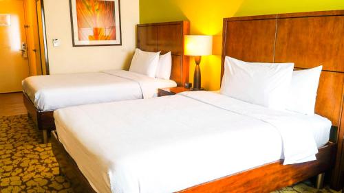 two beds in a hotel room with white sheets at Hilton Garden Inn Panama City Downtown, Panama in Panama City