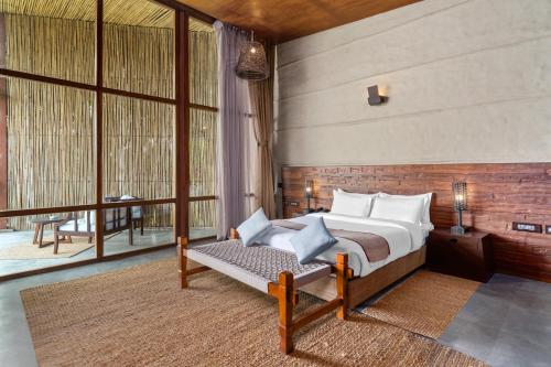 a bedroom with a bed and a large window at Sanctuary Chitwan National Park in Chitwan