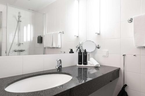 een witte badkamer met een wastafel en een spiegel bij Best Western Plus Park City Lund in Lund