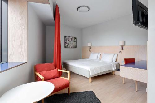 ストックホルムにあるBest Western Plus Park City Hammarby Sjöstadのベッドルーム1室(ベッド1台、赤い椅子付)