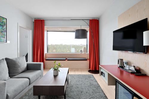 a living room with a couch and a tv at Best Western Plus Park City Hammarby Sjöstad in Stockholm