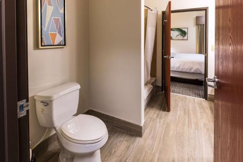 a bathroom with a white toilet and a bedroom at Comfort Inn & Suites New Iberia - Avery Island in New Iberia