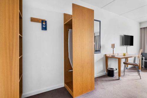 a room with a desk and a wooden closet at Best Western Plus Park Globetrotter Copenhagen Airport in Copenhagen