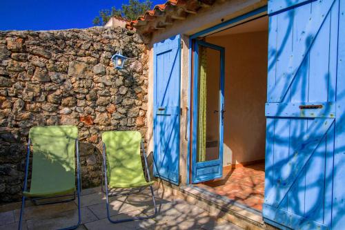 2 chaises vertes assises à l'extérieur d'un bâtiment en pierre dans l'établissement La Farigoule 68 person rental with shared pool nature and calm, à Flayosc