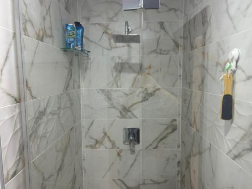 a bathroom with a shower with white marble tiles at Guest house Asta in Saparewo