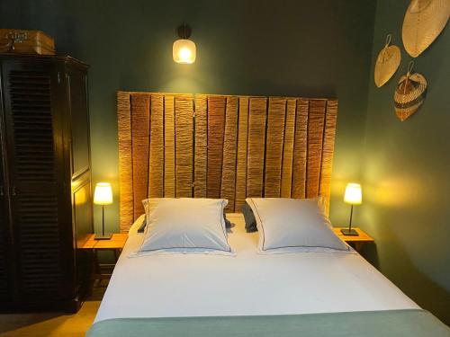 une chambre avec un lit avec deux oreillers et deux lampes dans l'établissement Un jardin en ville - Parking gratuit, à Lyon