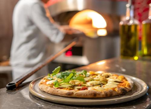 a pizza on a plate on a table at Elexus Hotel Resort & Spa & Casino in Kérynia