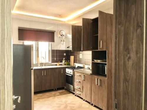 uma cozinha com armários de madeira e um forno com placa de fogão em Three Bedroom Homely Apartment em Lekki