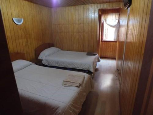 2 camas en una habitación pequeña con ventana en Hostal Lagunitas en Puerto Montt