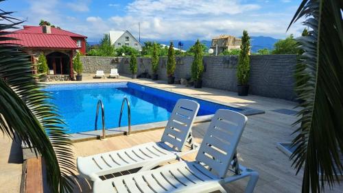 a swimming pool with two lawn chairs next to it at Emilia in Batumi