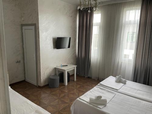 a bedroom with two beds and a tv on the wall at Emilia in Batumi