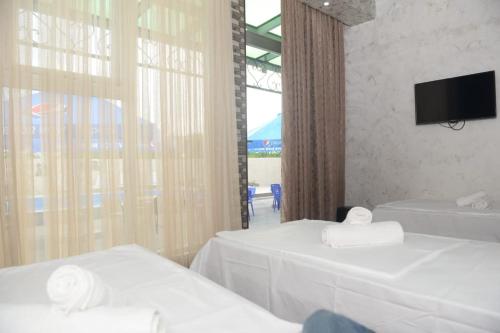 ein Hotelzimmer mit 2 Betten und einem TV in der Unterkunft Emilia in Batumi