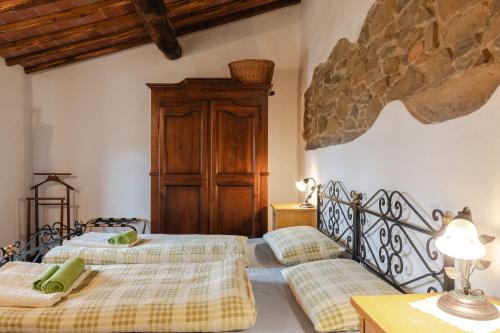 two beds in a bedroom with a stone wall at Reggioli- Appartamento Erborista in Gaiole in Chianti